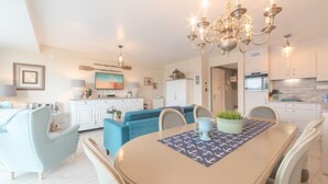 A modern living room with a dining table, blue sofa, and a chandelier. - L'Espérance d'autrefois by Interhome (Bredene)