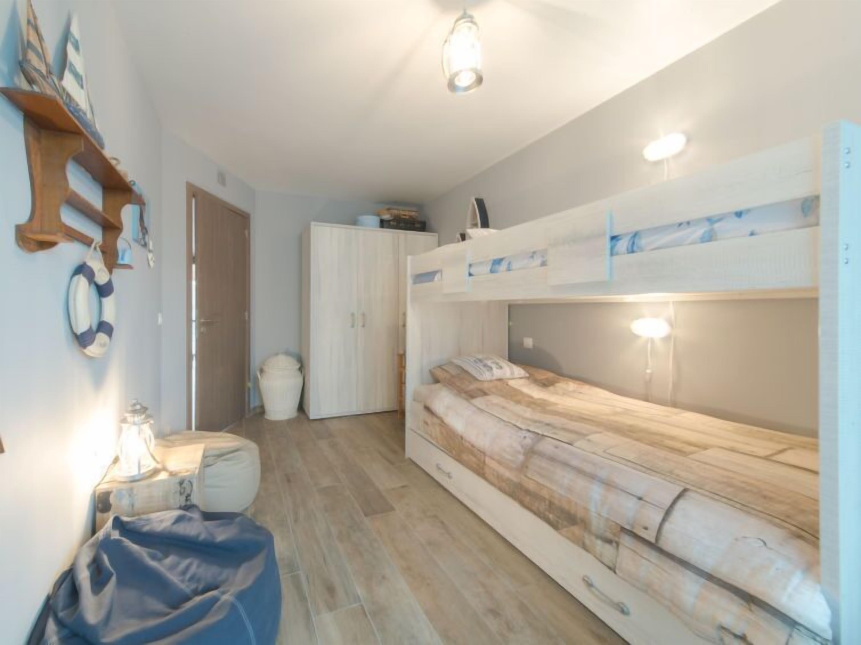 Une petite pièce avec des lits superposés, un petit bureau et une chaise.