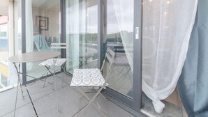 A balcony with a glass door, a small table, and a chair. - L'Espérance d'autrefois by Interhome (Bredene)