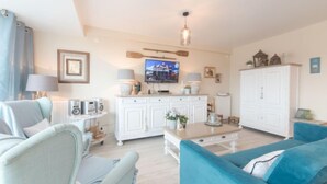 A living room with a sofa, chairs, a TV, a cabinet, and a ceiling light. - L'Espérance d'autrefois by Interhome (Bredene)