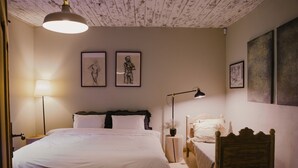 A bedroom with a bed, bedside tables, a chair, and artwork on the walls. - Newly renovated traditional farmhouse (Ģibuļi)
