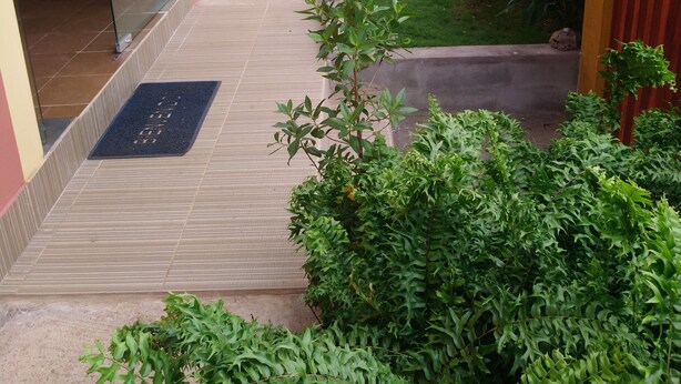 A residential building with a covered patio, a small garden, and a door leading to an interior space. - Hostal Terito (Puerto Baquerizo Moreno)