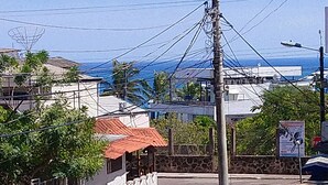 A street view with a building featuring a red roof and a small garden area. - Hostal Terito (Puerto Baquerizo Moreno)