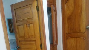 A wooden door leading to a bathroom with a sink and a mirror. - Hostal Terito (Puerto Baquerizo Moreno)