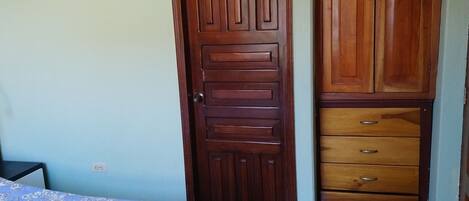 Un dormitorio con una cama, un armario de madera y una cómoda.