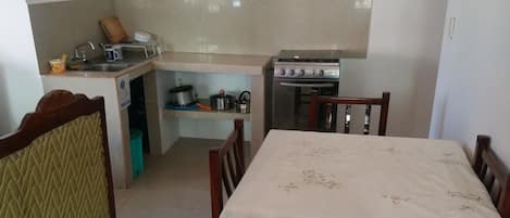 Cocina compacta con comedor, que incluye una mesa, sillas y estufa.