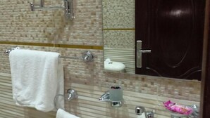 A bathroom with a large mirror, a sink, a towel rack, and a toilet. - New City Hotel (Cairo)