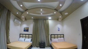 A bedroom with two beds, a ceiling with recessed lighting, and an air conditioning unit. - New City Hotel (Cairo)