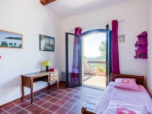 Ein Schlafzimmer mit Bett, Schreibtisch und einem Fenster mit Vorhängen.
