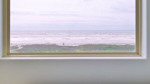 A room with a large window featuring a bamboo blind, a bed with white bedding, and a view of the ocean. - BEACHFRONT on 1 acre lot with incredible beach and bay views.  (Freeport)