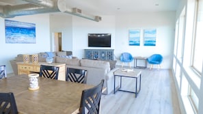 Una sala moderna con sofá, mesa de comedor, sillas, televisor y obras de arte en las paredes.