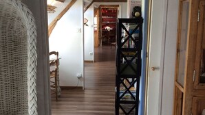 Un suelo de madera que conduce a una habitación con una silla de mimbre y un armario.