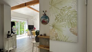 Una habitación amplia con piso de madera, un comedor con mantel amarillo y una gran obra de arte en la pared.