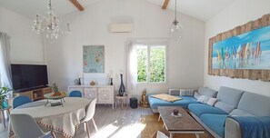 A living room with a TV, dining table, sofa, and artwork.