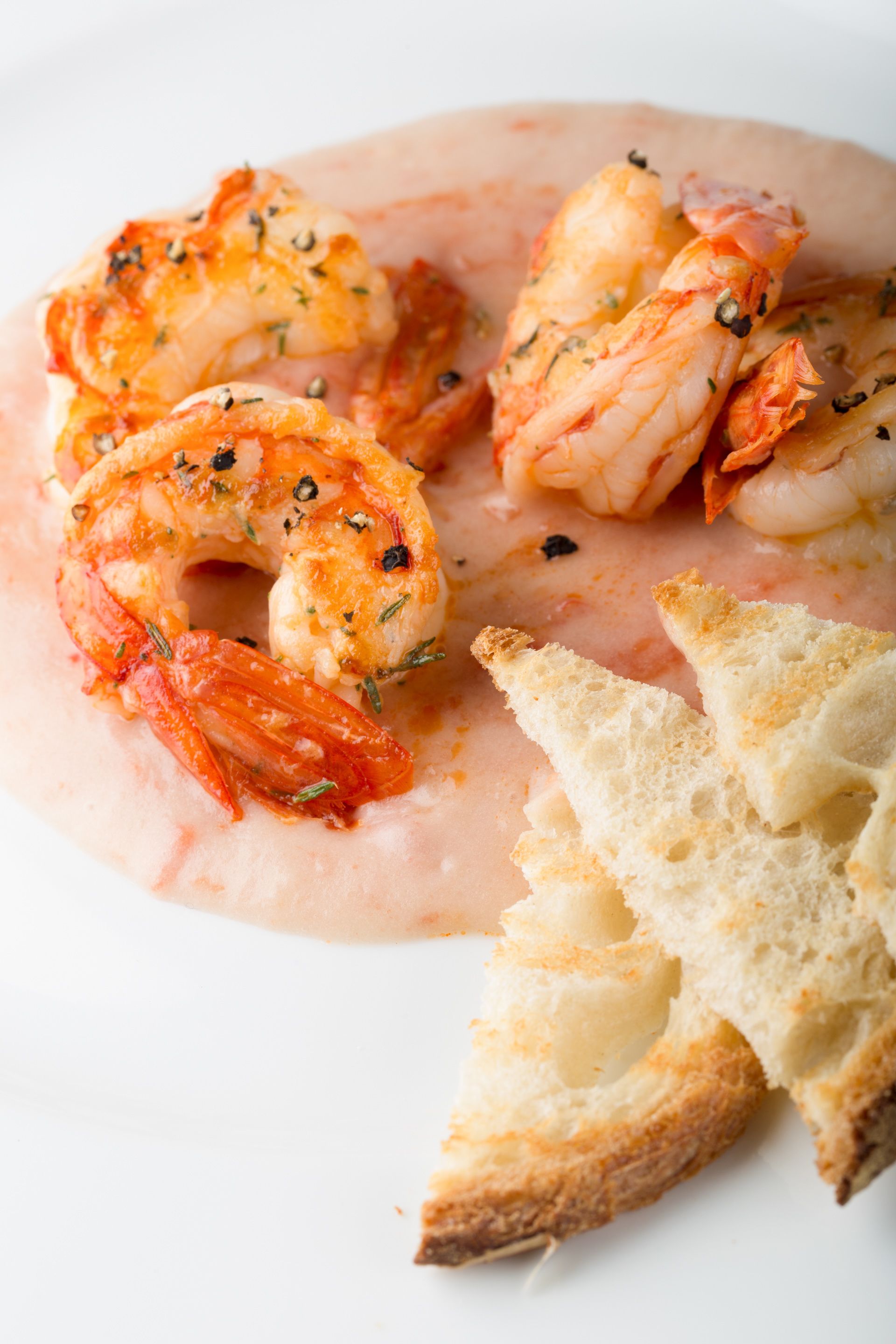 Une assiette de crevettes cuites et de pain grillé.