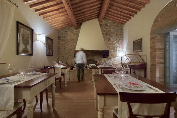 A restaurant with stone walls, wooden beams, and tables set for dining. - Villa San Sanino - Relais in Tuscany (Torrita di Siena)