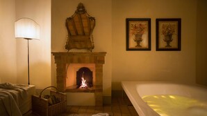 A bathroom with a fireplace, a bathtub, and two framed floral paintings on the wall.