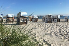 Cabañas de playa con toldos a rayas, dispuestas en filas sobre una playa arenosa con cielo despejado.