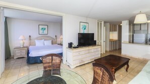 Habitación de hotel con cama, televisor en una cómoda, mesa de comedor y zona de cocina.