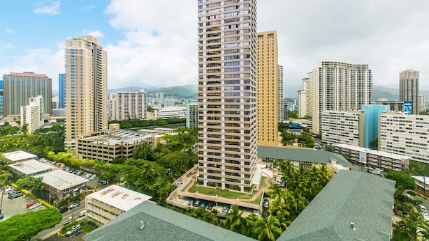 A high-rise building with a modern design, surrounded by other high-rise buildings and greenery.