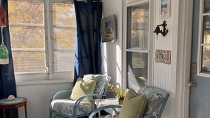 A cozy room with two blue metal chairs, a small table, and a rug. A door with a Florida license plate is visible.