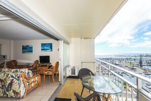 A balcony with a dining area, a TV, and a view of the marina.