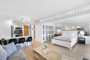 Et moderne hotelværelse med tekøkken, en stor seng, opholdsområde og udsigt over byen.