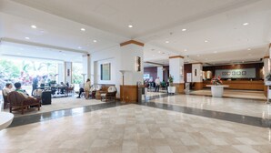 Un vestíbulo amplio con una recepción, zonas de estar y un mostrador de check-in.