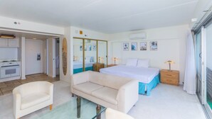 Quarto de hotel com uma cama, um sofá, uma mesa de vidro, uma mesa de cabeceira de madeira e um espelho.