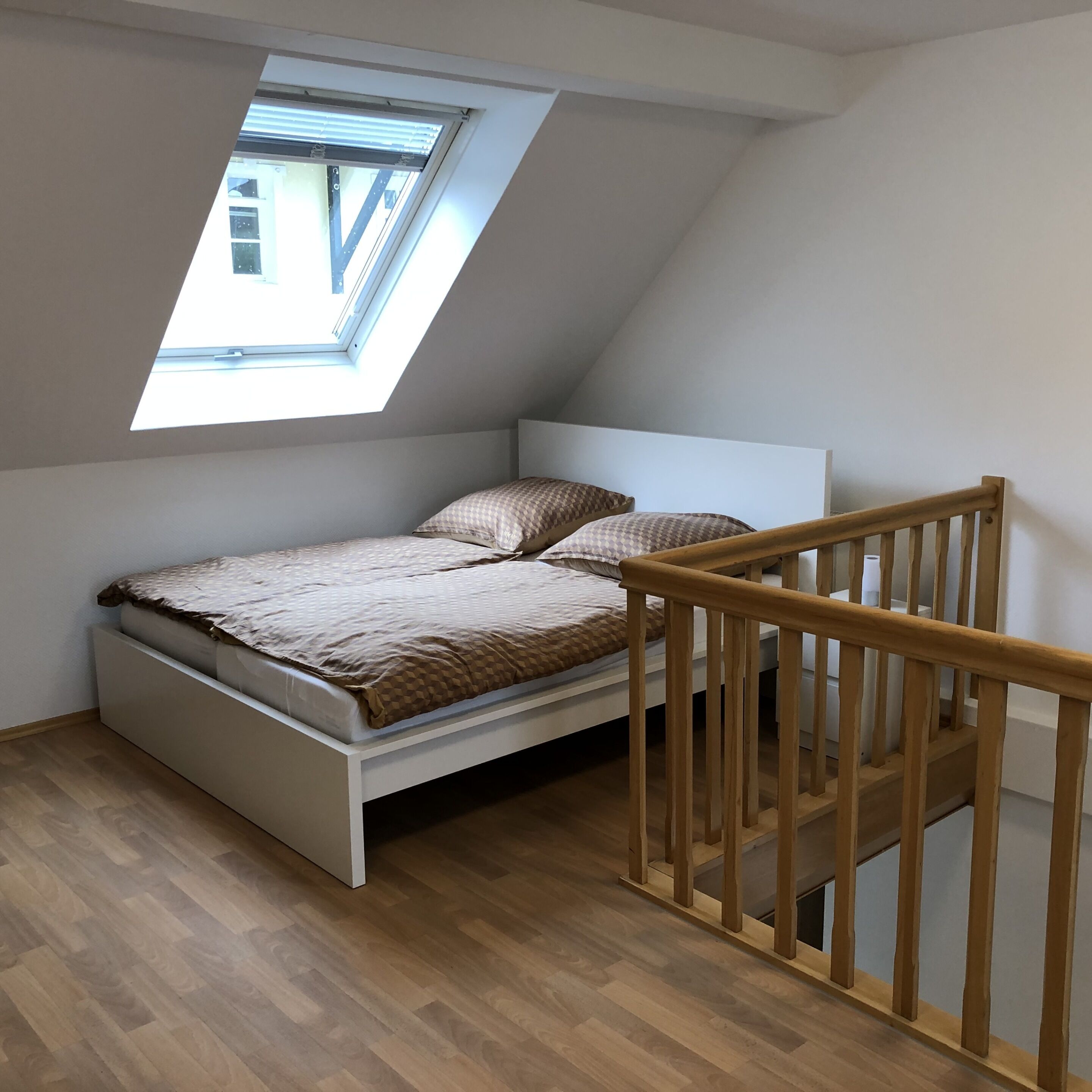 Ein Einzelbett mit Holzvorzelt und einem Oberlicht darüber.