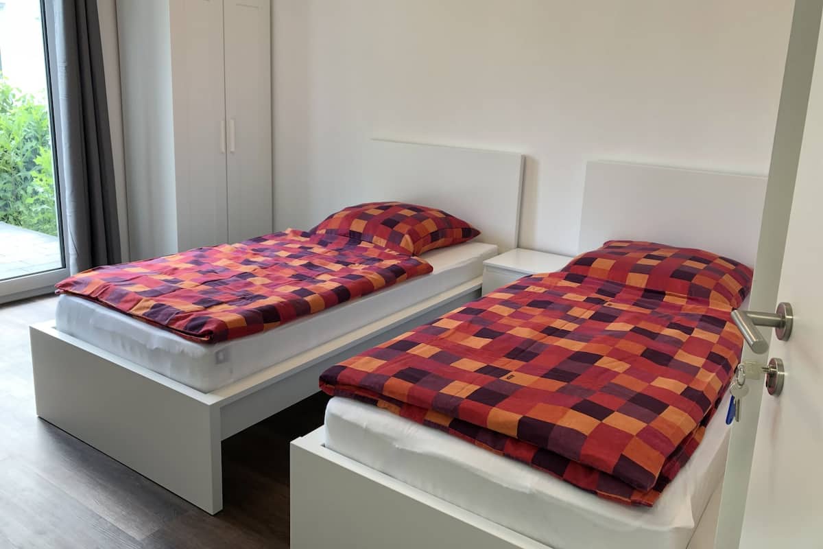 Ett hotellrum med två separata sängar, en garderob och utsikt över grönområden utanför.