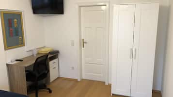 Une pièce comprenant un bureau, une chaise, un téléviseur, une armoire et un tableau encadré au mur.
