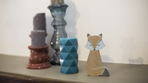 A shelf with three decorative items: a candle, a geometric blue candle, and a wooden fox figurine. - Pair of studio apartments in the Langhe with swimming pool, panoramic terrace and green area (Cossano Belbo)