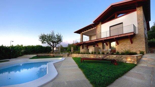 A modern two-story house with a swimming pool, a stone retaining wall, and a well-maintained lawn. - Pair of studio apartments in the Langhe with swimming pool, panoramic terrace and green area (Cossano Belbo)