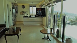 Een moderne keuken met een groot raam, een eethoek met tafel en stoelen, en een woonkamer met een bank en een televisie.