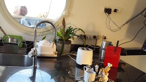 Een keuken met een gasfornuis, een spoelbak, een raam en een potplant.