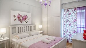 A bedroom with a bed, nightstands, a wardrobe, a chandelier, and a window with curtains. - Margarita's home cozy home! (Athina)