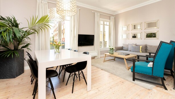Ein modernes Wohnzimmer mit Essbereich, einer Couch und einem Fernseher.