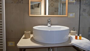 A bathroom with a round white sink, a mirror, and a towel rack. - ChocoHouse (Ragusa)