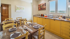 A dining area with yellow cabinets, a breakfast bar, and a view of the outdoors. - ChocoHouse (Ragusa)