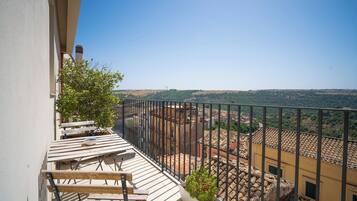 A balcony with a view of a town and hills.