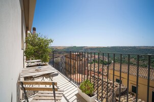 Un balcón con vista a un pueblo y colinas.