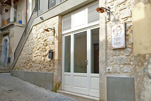 Un edificio de piedra con una puerta blanca y un letrero que indica que alberga una chocolatería, cafetería, habitaciones y una fábrica.