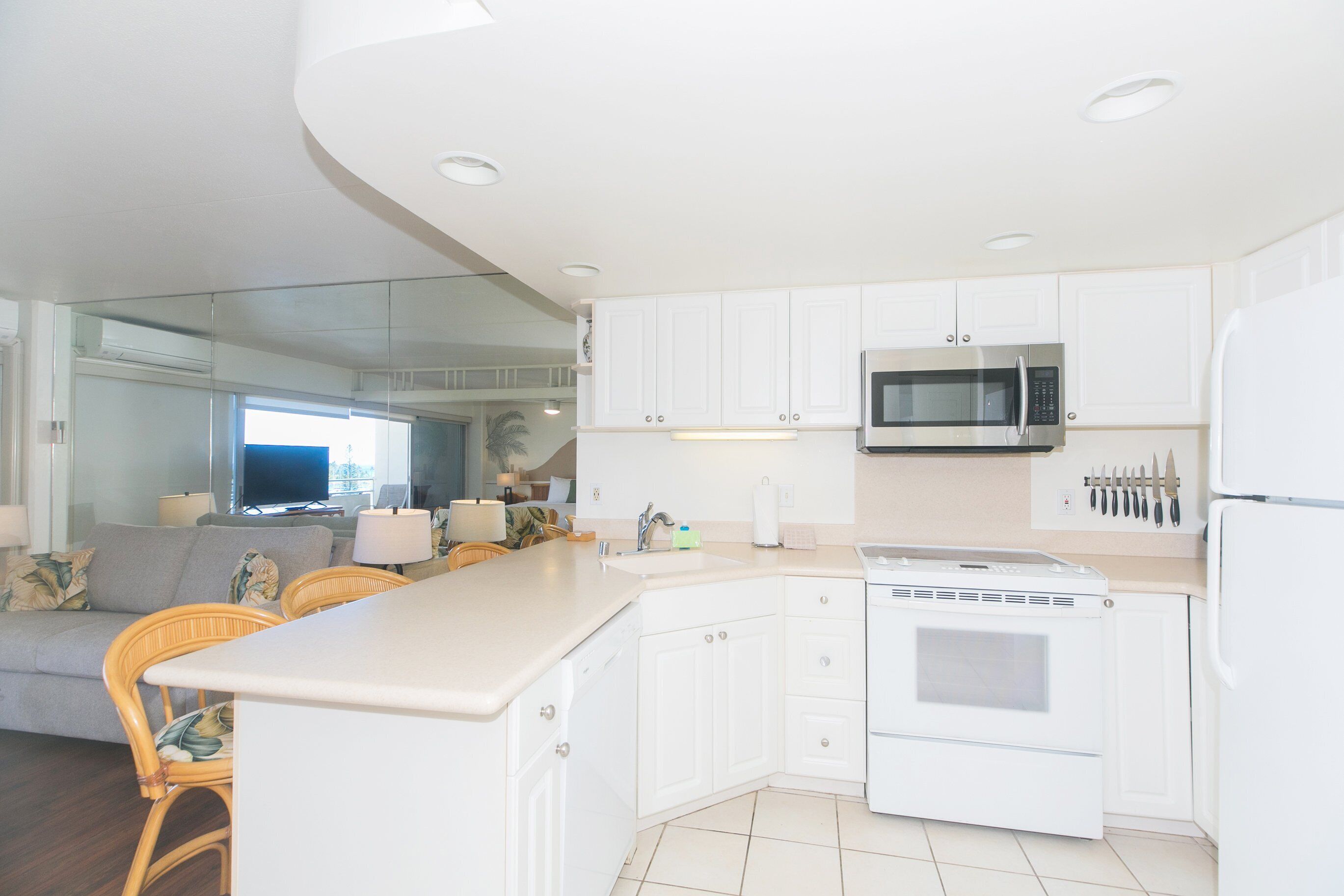 A modern kitchen with white cabinets, a microwave, an oven, and a refrigerator.