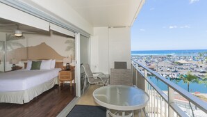 A balcony with a bed, a table, and a view of the marina and ocean. - Ilikai Hotel One-Bedroom Suite in a Great Location In Waikiki!  No Resort Fees! (Honolulu)