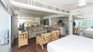 A spacious room with a bed, a sofa, a dining table with chairs, and a kitchen area. - Ilikai Hotel One-Bedroom Suite in a Great Location In Waikiki!  No Resort Fees! (Honolulu)