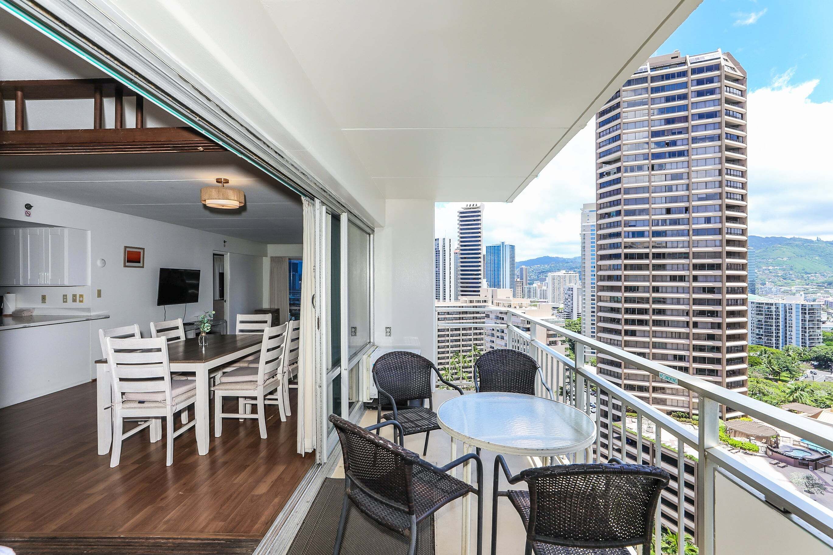 A balcony with a dining area, a TV, and a view of tall buildings.