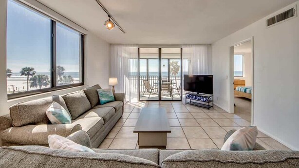 Una sala moderna con sofá, mesa de centro, televisor y un balcón con vistas.