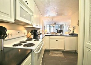 A kitchen with white cabinets, a stove, and a sink.