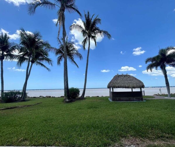 A beach view with palm trees and a thatched structure.